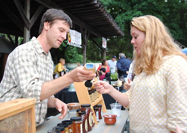 Local beekeeper Ryan Higgs serves a sample of honey to junior nursing major Emily Williams at the Watauga County Farmers Market Saturday morning. The market is currently open Saturday and Wednesday mornings from 8:00 a.m. to noon at Horn in the West. Olivia Wilkes | The Appalachian