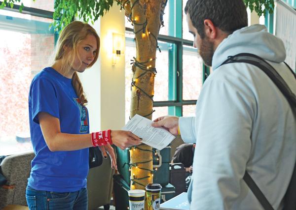 Senior political science major Lia Poteet hands senior political science major Johnny McElhany some information about the upcoming election at Mondays Rock the Vote event. The event, held from 11-4 in the Solarium, encouraged students to vote and offered free food, speakers and live music. Maggie Cozens | The Appalachian