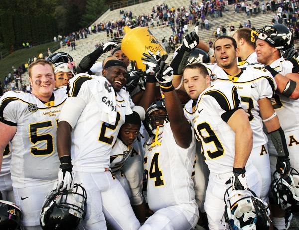 Members of Mountaineer offensive line celebrate their win with the Old Mountain Jug on the field Saturday. The team pounced the Catamounts for a 38-27 win. Paul Heckert | The Appalachian