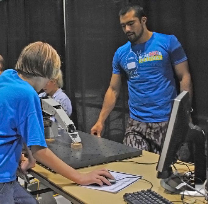 Graduate student Brayam Pinilla demonstrates his robotic arm to a middle school student during the Science Discovery Day at Holmes Convocation Center. The event, held in correlation with the North Carolina Science Festival, aimed to promote the fun and occupational practicality of science and math to young students. Nicole Debartolo | The Appalachian