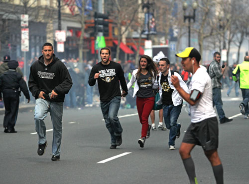 Spectators flee from the scene of the first of two explosions that shook the finish line of the 117th Boston Marathon near Copley Square on Monday afternoon. The bombings left three dead and 140 injured as of press time. Kenshin Okubo | Daily Free Press