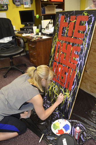 Senior public relations major Jennifer Gallimore paints a sandwich board to advertise the first Tie Dye Dash taking place April 27 at Duck Pond Field. Aneisy Cardo | The Appalachian