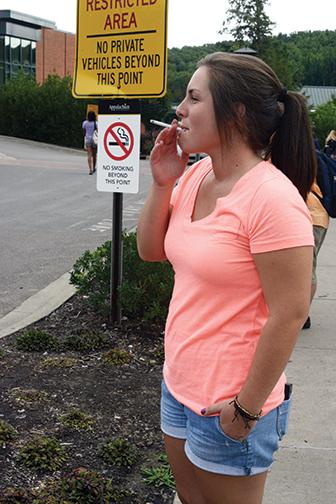 Senior psychology major Lindsay Livengood takes a smoke break at College Street Circle. This is a newly enforced designated smoking area as of fall 2013. Photo by Courtney Roskos | The Appalachian