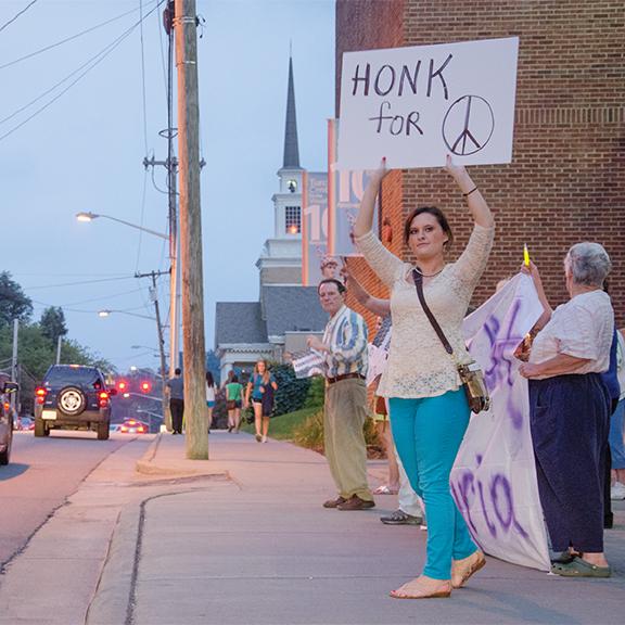 Senior political science major Jenny Church holds a sign advocating for peace during MoveOn’s vigil Monday against a United States military strike in Syria. Photo by Justin Perry | The Appalachian