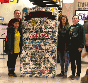 (From left to right) Aakriti Agrawal, Julia Grainger, Brie Sciales and Rachel Clay pose with a mattress used for the mattress walk in Plemmons Student Union on Wednesday. The mattress walk was held to raise awareness for sexual and domestic violence in the college community. Photo by Carson Hager  |  The Appalachian