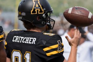 Punter/place kicker Bentlee Critcher spins a ball on his fingertip on the sideline. Photo By: Monique Rivera, Photographer 