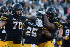 Freshman offensive line Victor Johnson and junior offensive line Colby Gossett meet Sophomore running back Jalin Moore in the end zone after Moore's touchdown.