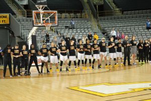 Appalachian State Women's Basketball team lines up for the National Anthem. The team is wearing their t-shirts to show support for their Coach Angel Elderkin who was diagnosed with cancer.