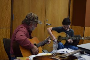 Renowned guitar maker Wayne Henderson jamming with a young guitarist at the luthiers' gathering.