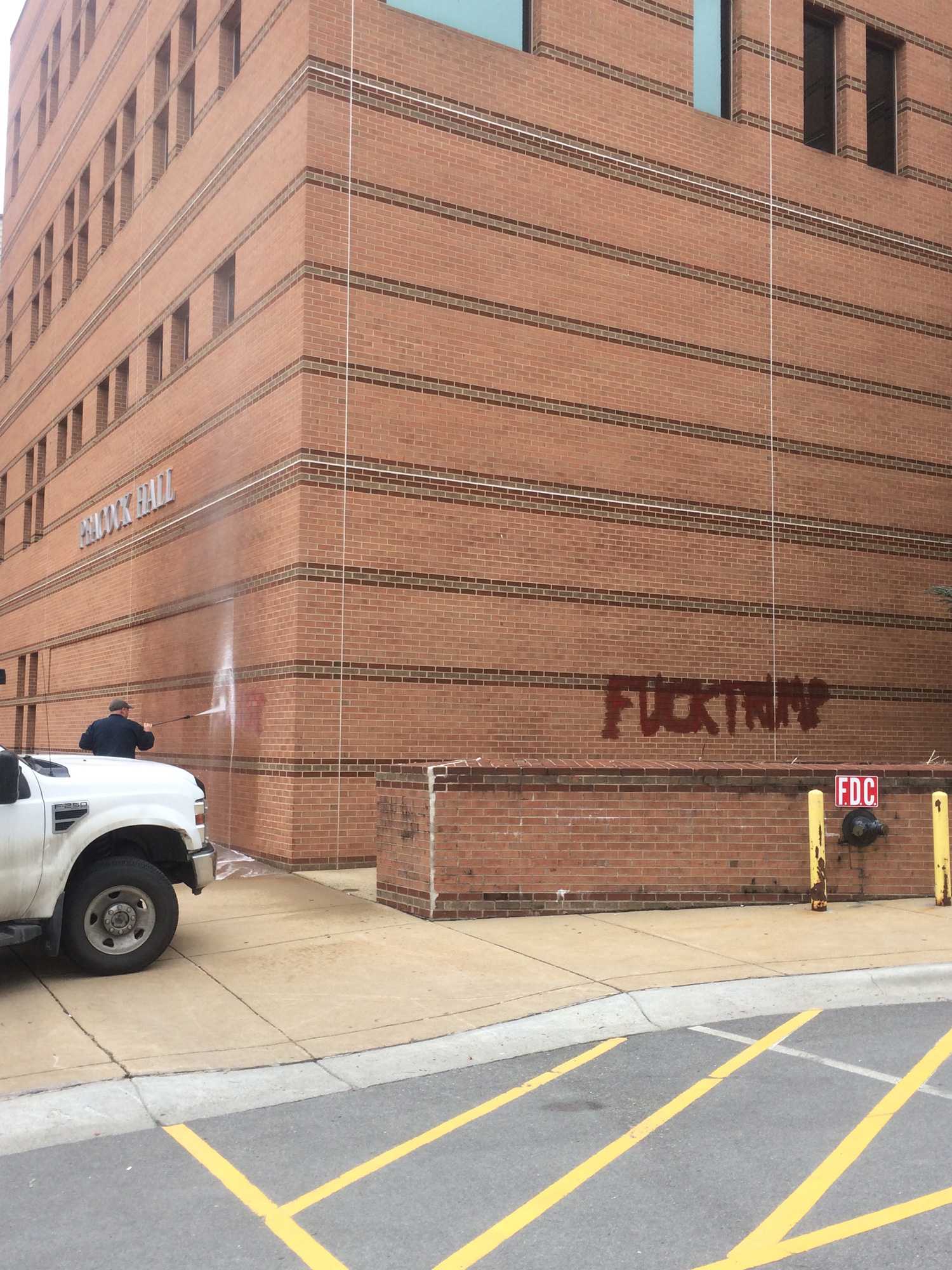 A worker washing off vandalism on Peacock Hall. Four different people wrote words on multiple buildings around the Town of Boone