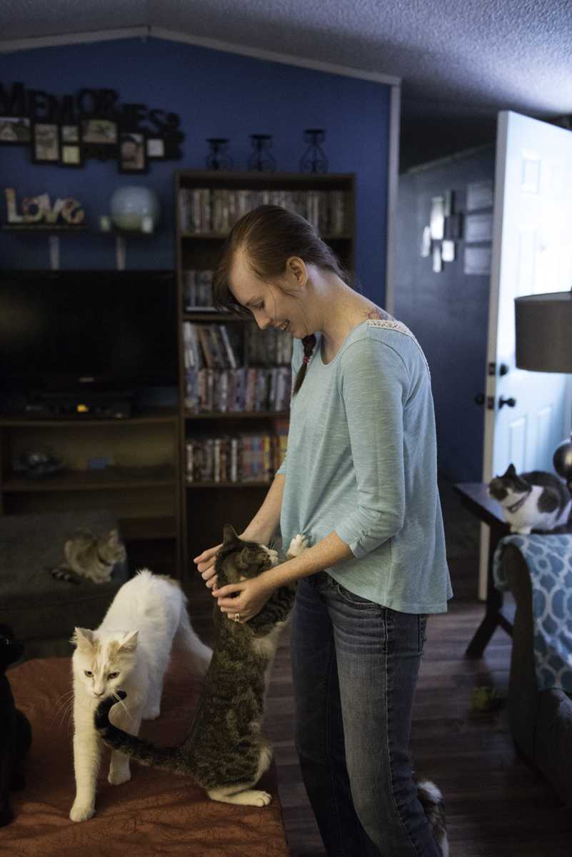 Kourtney Wunsch, co-founder of Love, Bones, and Furever Homes plays with one of the many rescued cats inside her home. Currently, there are approximately 30 cats in here house. Photo by Justin Perry.