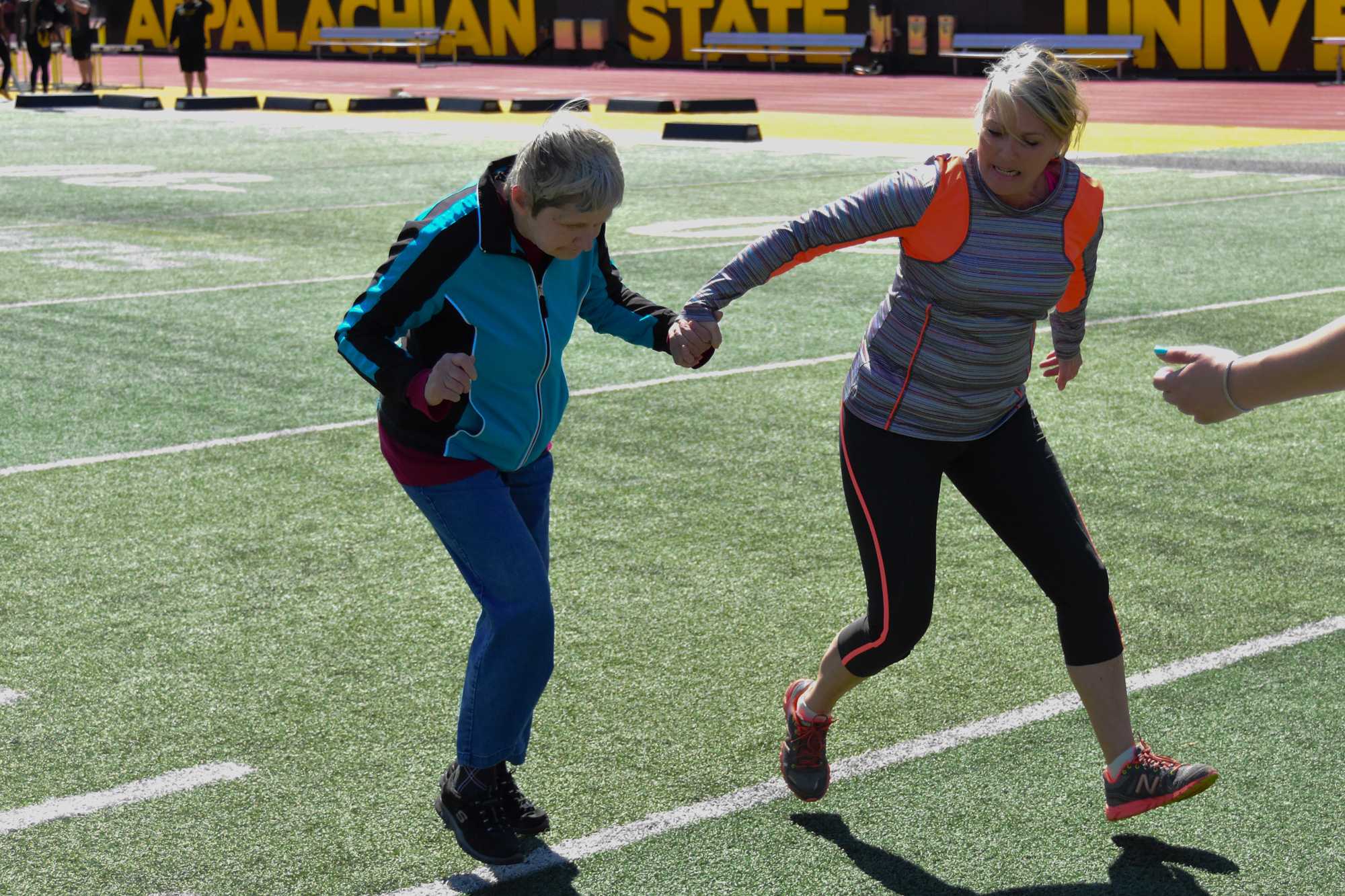 Karen Poteat assists Ava Trivette in the long jump during track and field practice. Photo by Lee Sanderlin.