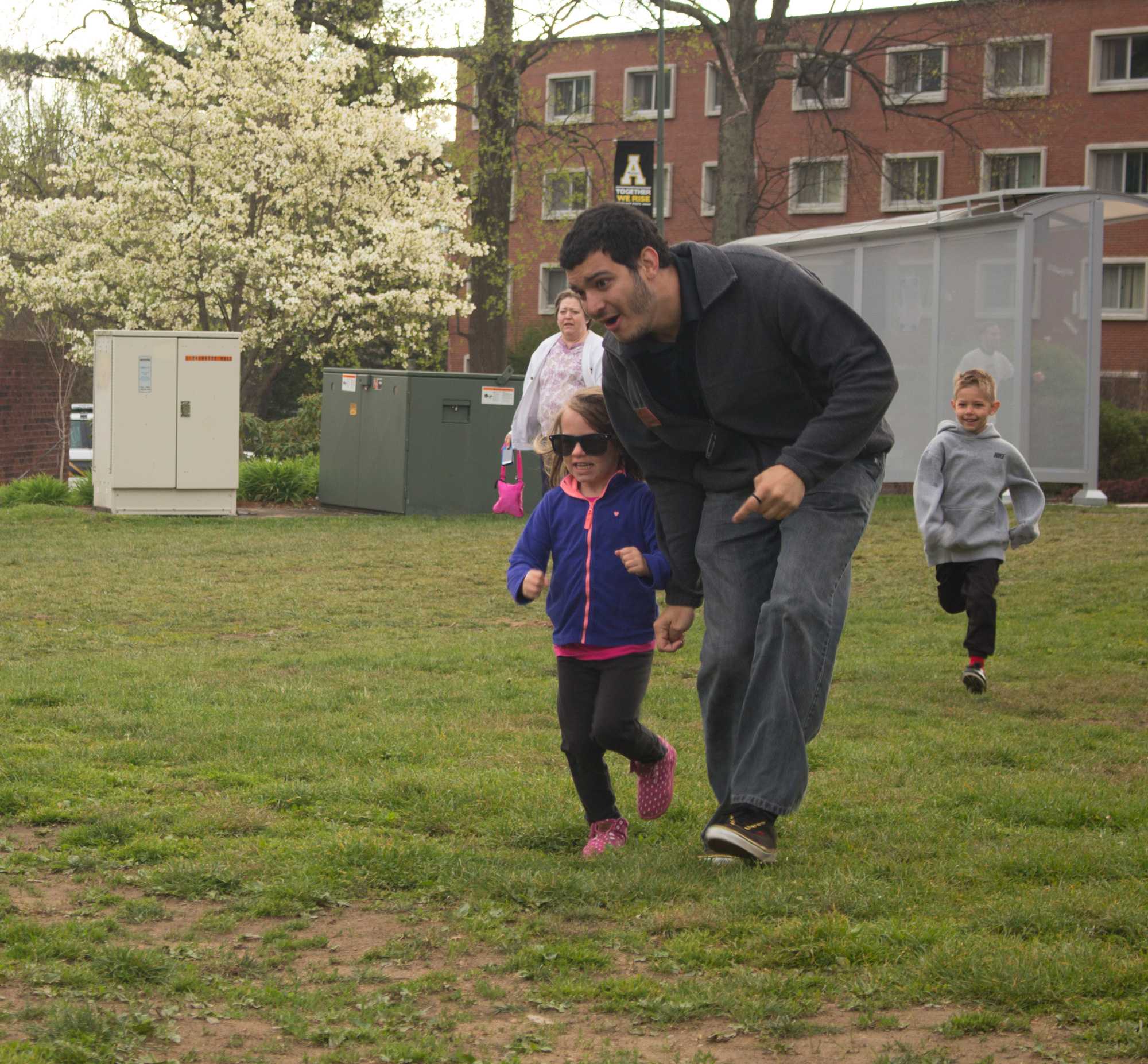 Freshman Brazilian international student Artese Murilo helps a young girl cross the finish line. Photo by Aaron Moran.