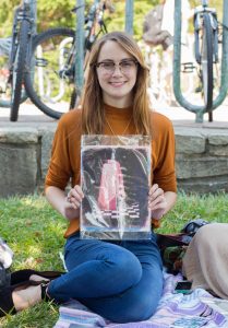 Katelyn Cartwright, Shauna Caldwell's friend and participant in the art drop is holding a piece of artwork she found under a stairwell on campus.