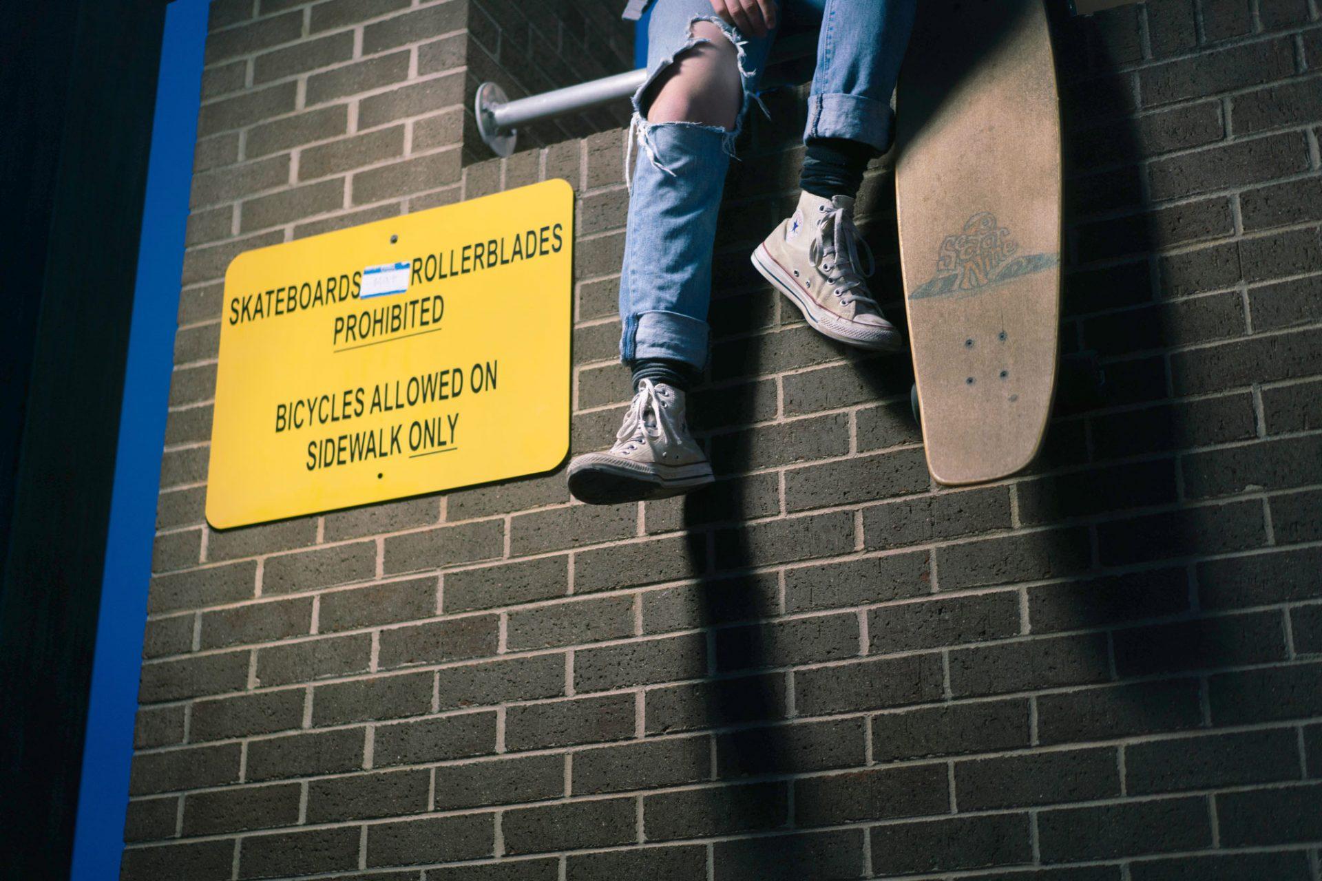 A sign prohibiting skateboards and rollerblades is posted on the side of the Miles Annas Student Support building. 
