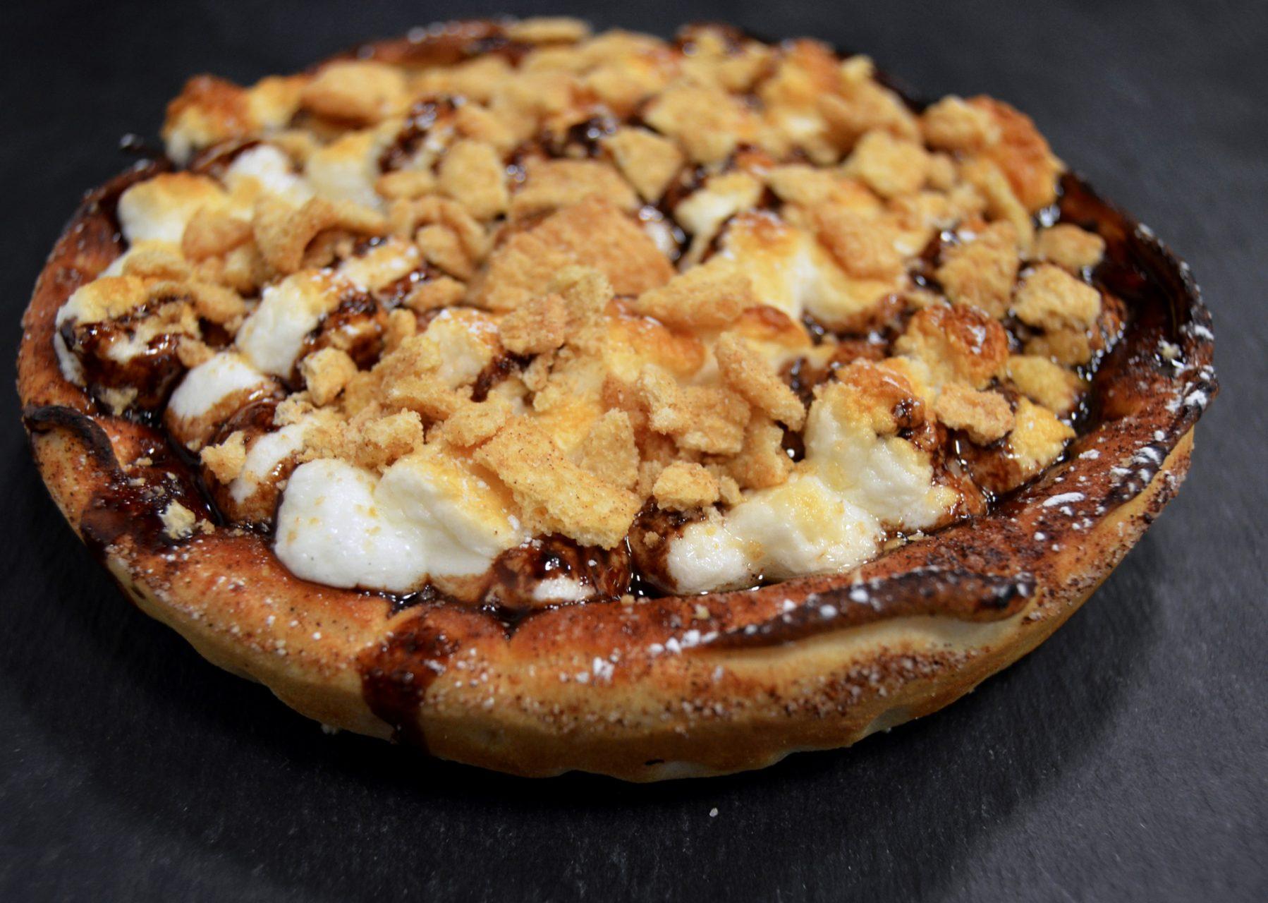 The smores dessert pizza is made at The Pizzeria of Roess Dining Hall. Its a 10-inch deep dish pie with marshmallows, chocolate syrup, and Capn Crunch cereal on top. 