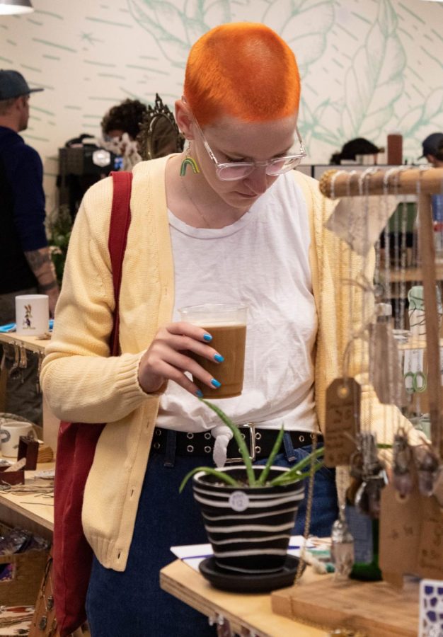 Lizz Henry, a senior religious studies major, sifts through a stand while enjoying her coffee at Pop Up Boone this weekend. The monthly event took place this past weekend at Hatchet Coffee off of Bamboo Road.