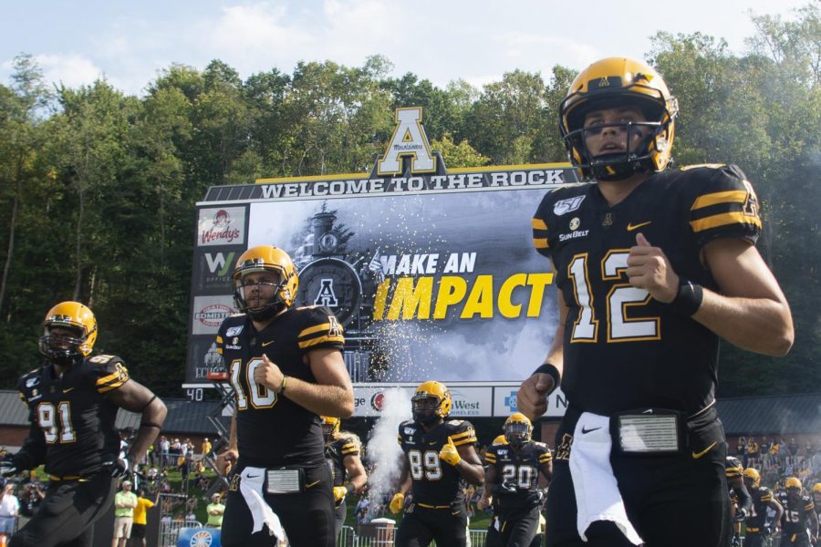 Quarterback+Zac+Thomas%2C+this+years+Sun+Belt+preseason+offensive+player+of+year%2C+%28far+right%29+leads+App+State+onto+the+field+before+a+56-37+victory+against+Coastal+Carolina+on+Sept.+28.