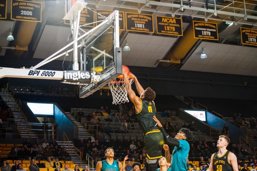 Senior forward Isaac Johnson dunks the ball over a defender in the Mountaineers game against Coastal Carolina. Johnson recently scored his 1000th career point this season and feels it is a blessing.