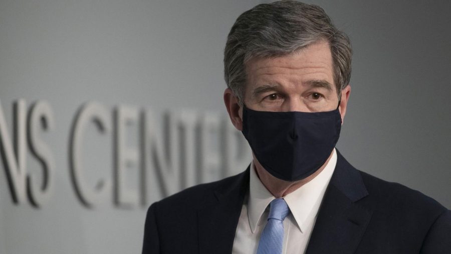 Gov.+Roy+Cooper+dons+a+face+mask+at+a+press+briefing.