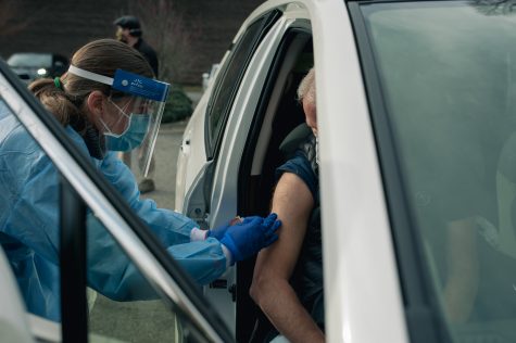 Melinda Bogardus, a family nurse practitioner, administers the Moderna vaccine to a patient in the parking lot of AppHealthCare.