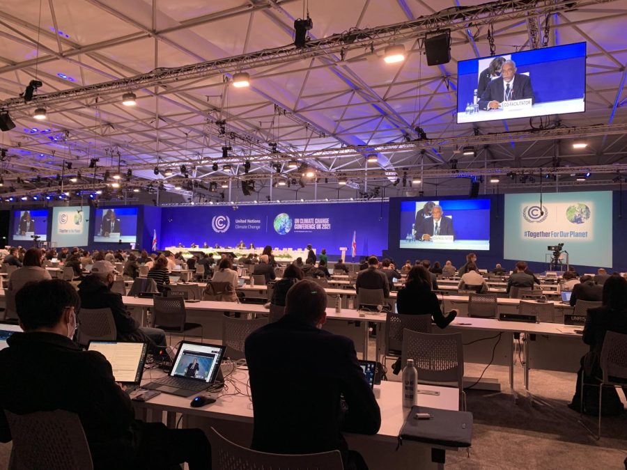 Attendees sit in for a panelist session and listen to facilitators at COP26. 