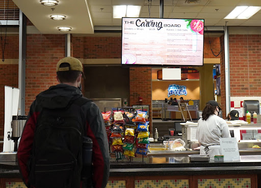 A student stands in front of the Carving Board in Roess Dining Hall as their meal is prepared Feb. 3, 2022.
