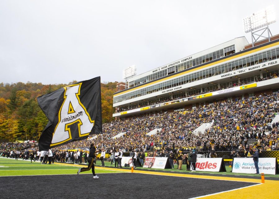 Senior cheerleader Hector Sanchez running through the end-zone carrying the App State flag after a touchdown.