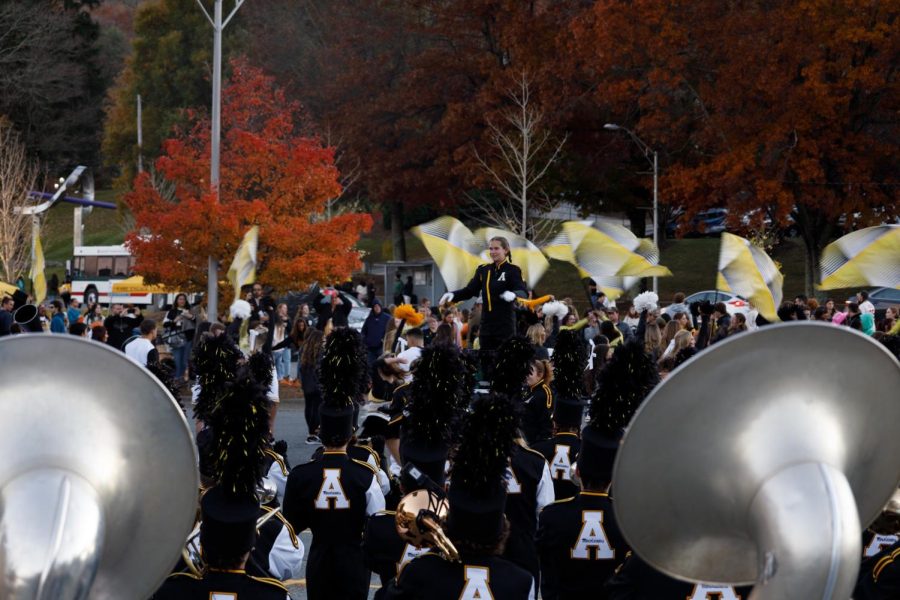 The App State marching band stopped in the Peacock Lot to perform songs such as The Incredibles and Spider-Man theme songs. Cheerleaders perform behind the composer for the onlooking crowd.