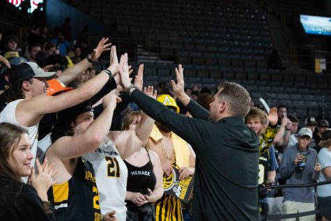 Head coach Dustin Kerns high fives the Mountaineer student section after App State defeated Warren Wilson 142-74 Nov. 7, 2022.