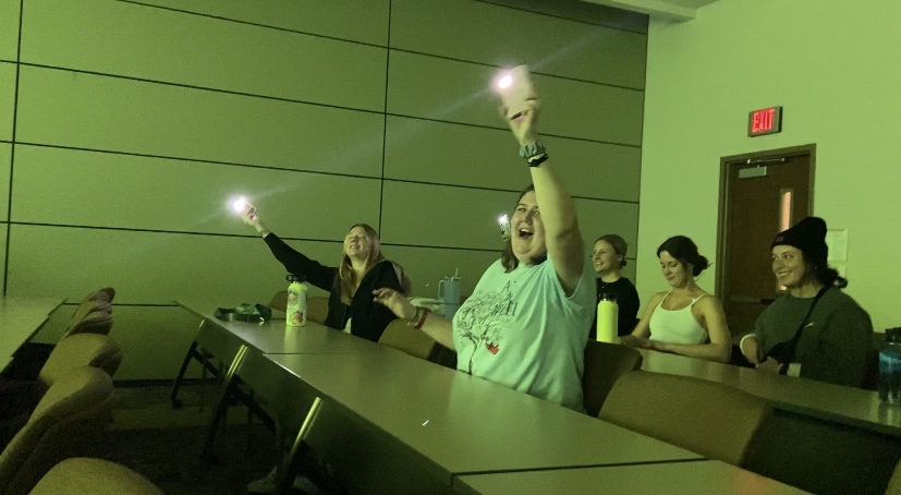 Students wave their cell phone flashlights during one of the performances in the talent show.