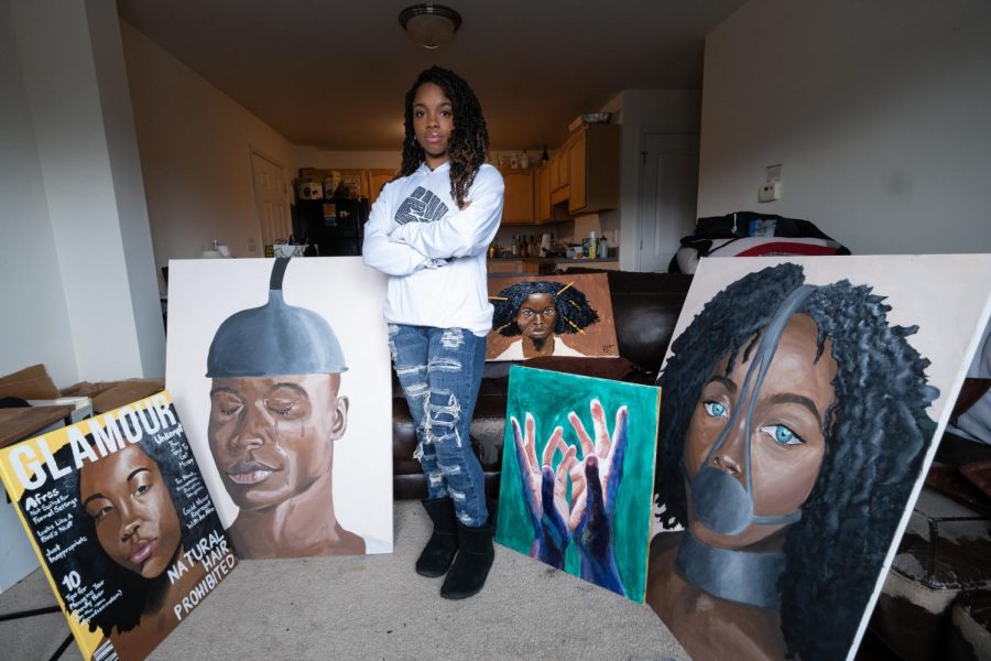 Jelonnie Smith poses with her favorite pieces Feb. 24, 2022. Her most recent project focuses on wrongful incarceration, featuring the two larger portraits pictured.