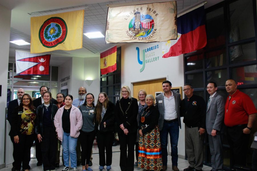 Members of the Lumbee Tribe standing with members of App State faculty, underneath the Lumbee Tribe flag. 