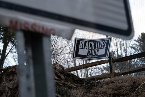A Black Lives Matter sign stands in the front yard of a resident of the Junaluska neighborhood, right under a 25 mph speed limit sign, with a torn off missing poster. 