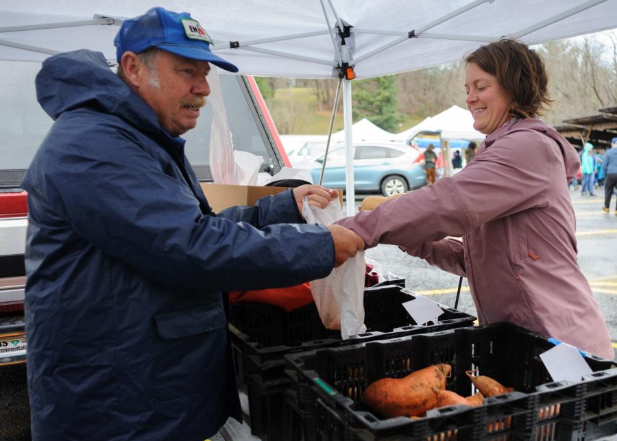 Bill Moretz, owner of Moretz Mountain Orchard and Farms, sells produce to Mallie Billing at the Watauga County Farmers Market on Saturday, April 1, 2023.