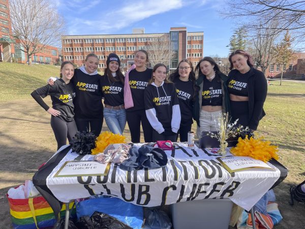On Nov. 13, 2023, members of the Appalachian State Club Cheer team pose together at their table on Sanford in between greeting guests and selling items. The Cheer Club is raising money for their next Daytona trip where they practice, compete, and bond. Photo by Abby Buckner.