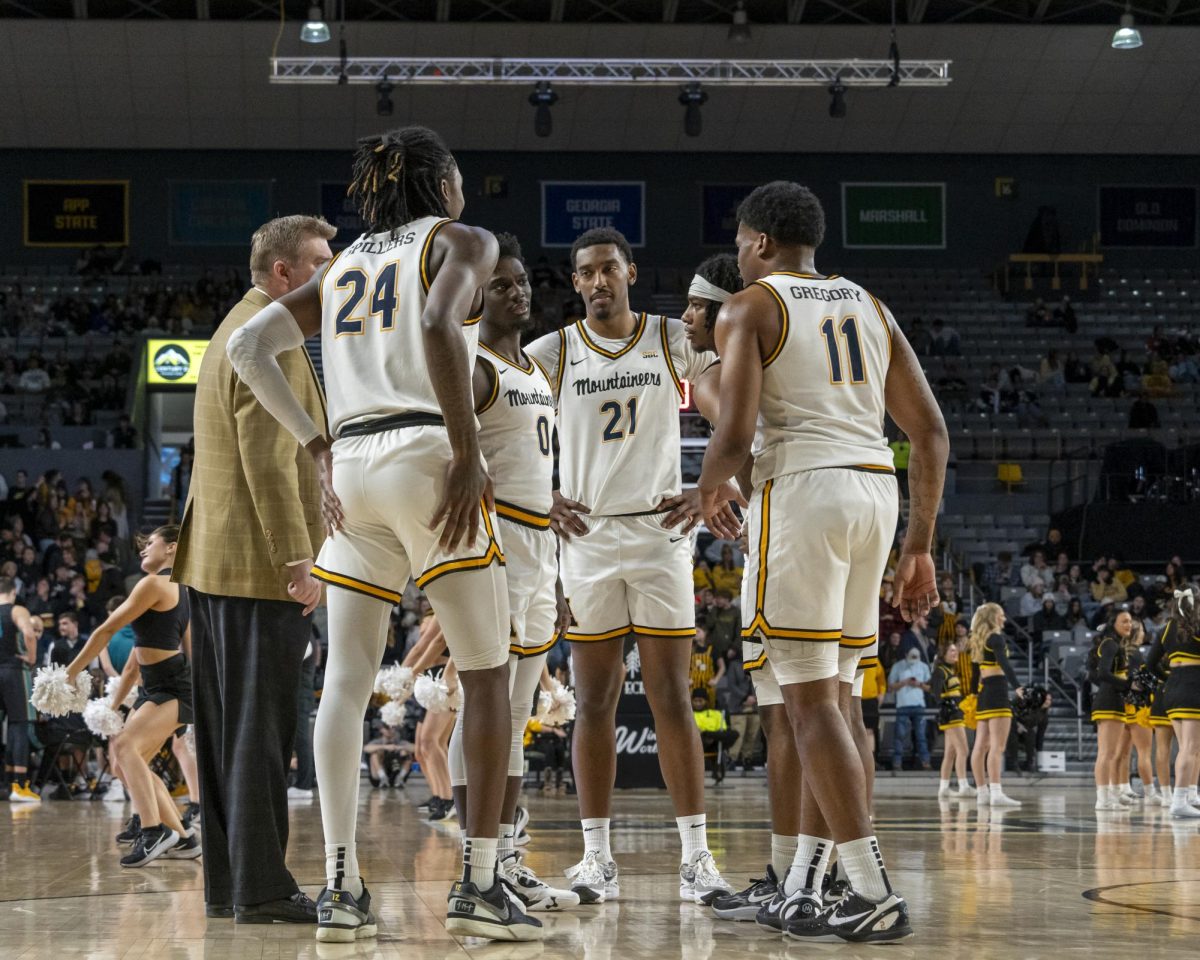 Head coach Dustin Kerns meets with his players during a timeout against Coastal Carolina Jan. 20.