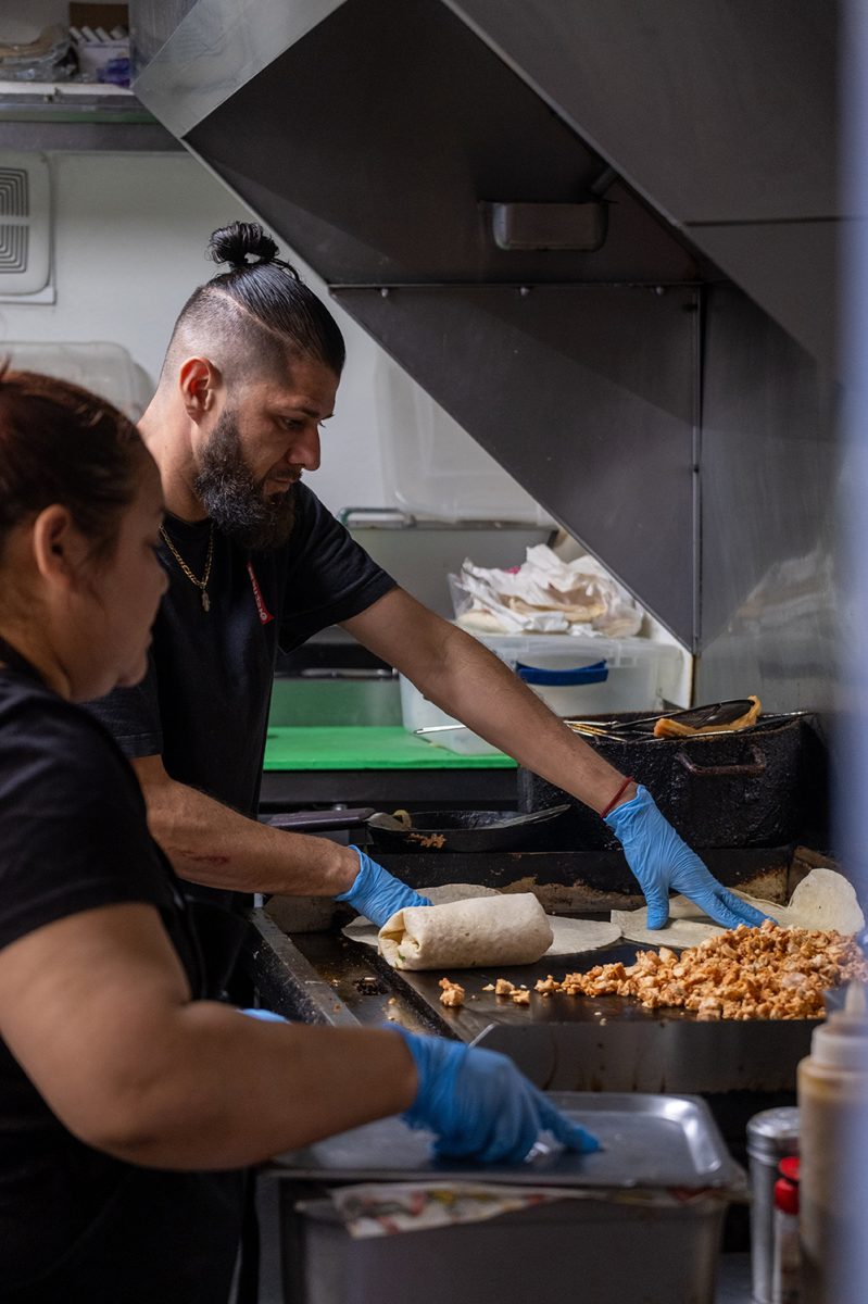 Owner Alex León works on making one of El Tacorriendo’s most popular menu items, the ACP burrito, on April 2.