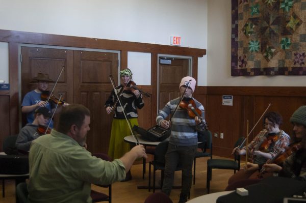 Professor Alex Hooker guiding his students through bow movements while practicing a song. Feb. 14, 2024. Hooker’s Appalachian Strings class features both fiddles and banjos, which are taught simultaneously in different parts of the room. 