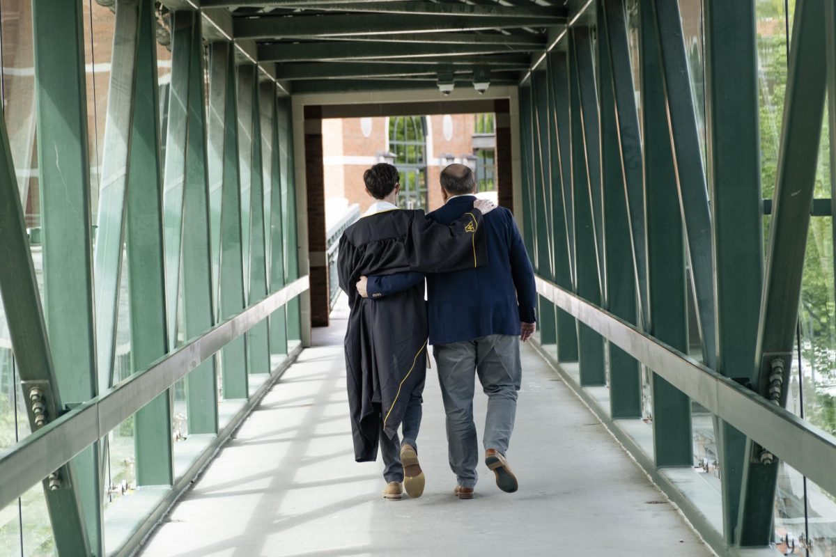 A recent graduate embraces their father after commencement on May 11 on the skywalk bridge.