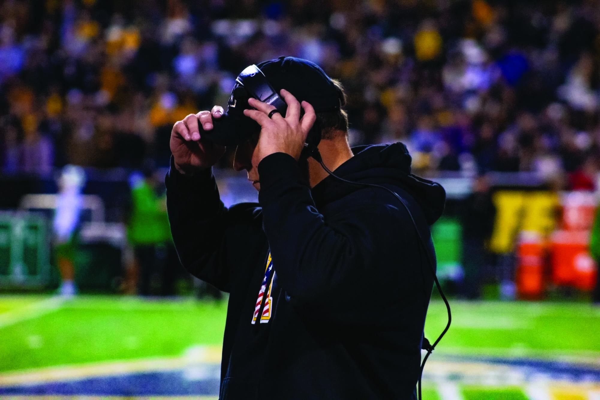 Football coach Shawn Clark adjusting his headset at Kidd Brewer Stadium on Nov. 4. During Clark’s football career in college, he was a two-time All-American and three-time all-conference selection.