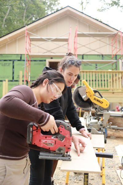 Site leader Sarah Grady and App State student Kennedy Chunley use a table saw to cut a piece of siding for a Habitat for Humanity home on Sept. 7. Volunteers worked together to put up siding on the back of the house.