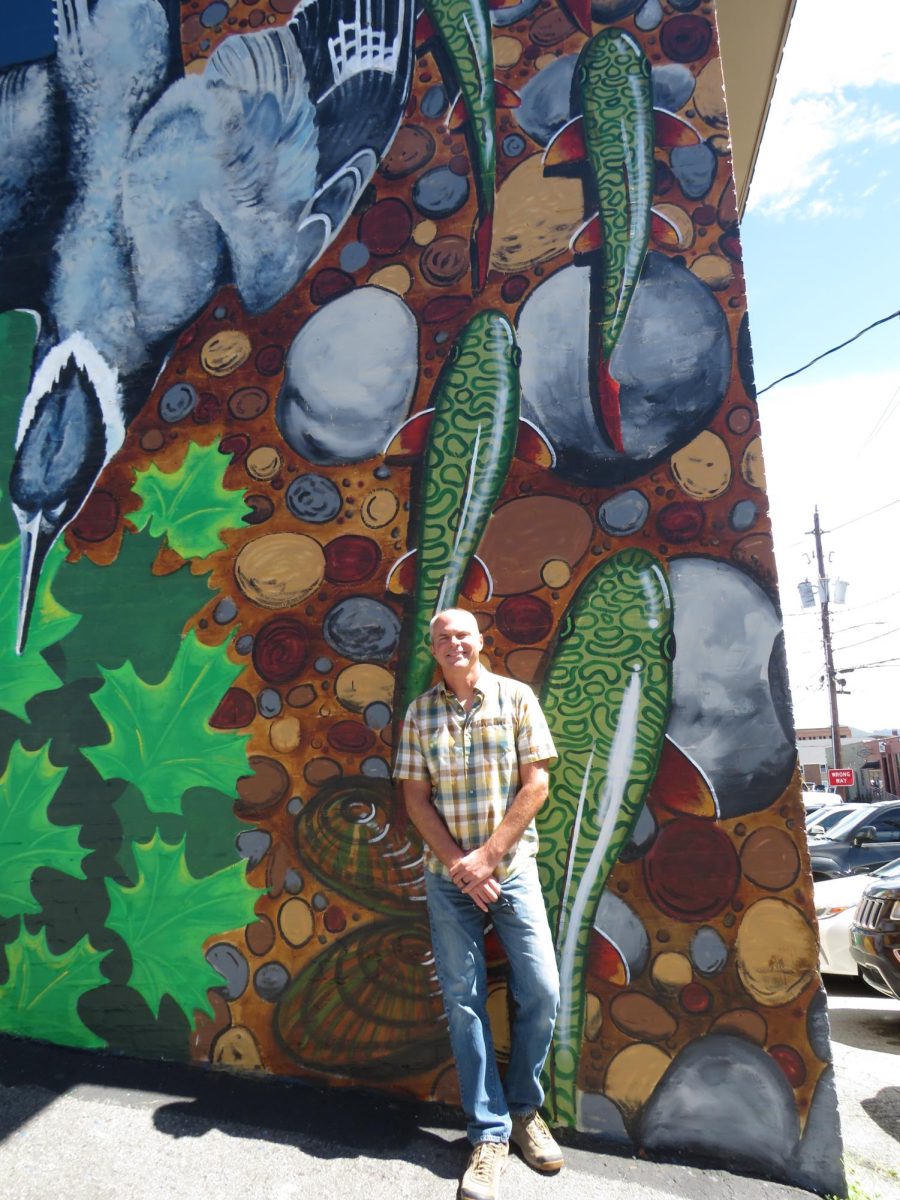 Josh Johnston poses next to his newly unveiled mural located on Howard Street on Sept. 4. Johnston’s mural features the hellbender salamander, a species found in the rivers and streams of the Appalachian Mountains.