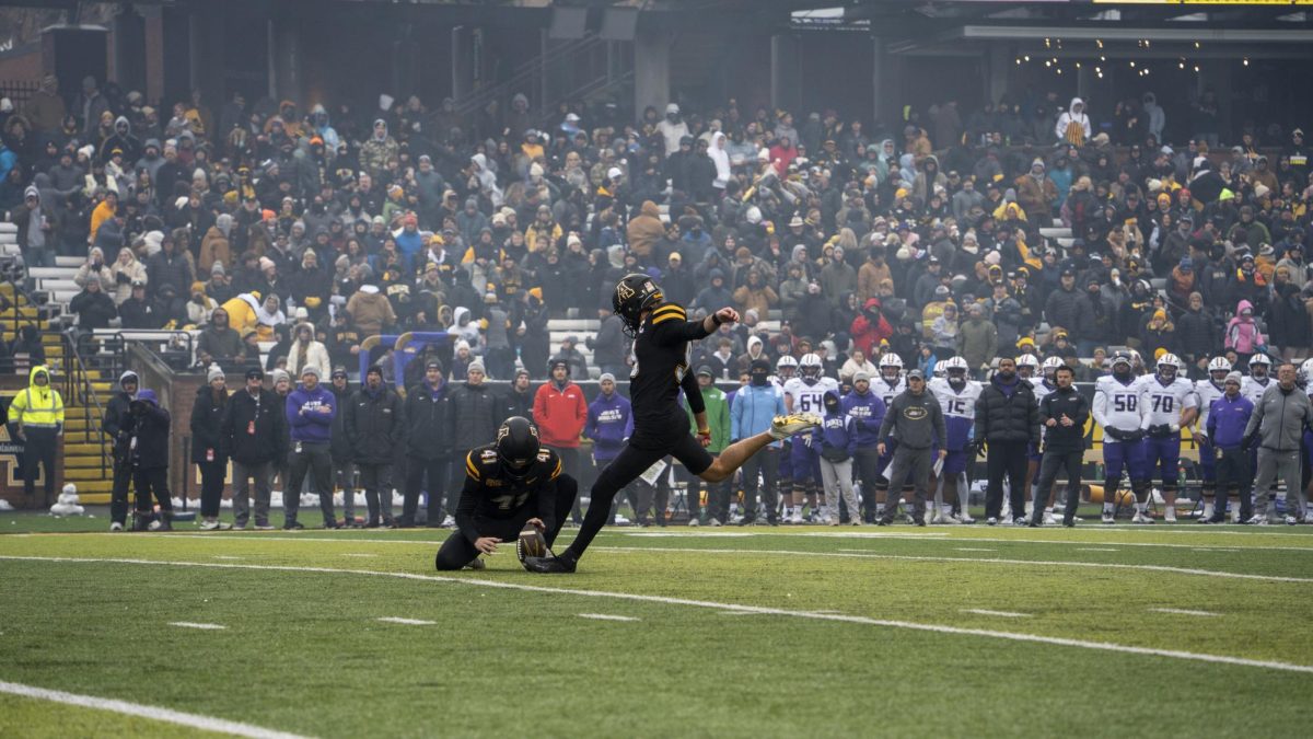 Kicker Michael Hughes attempts a point-after touchdown kick with Connor Maynard assisting in holding the ball on Nov. 23.