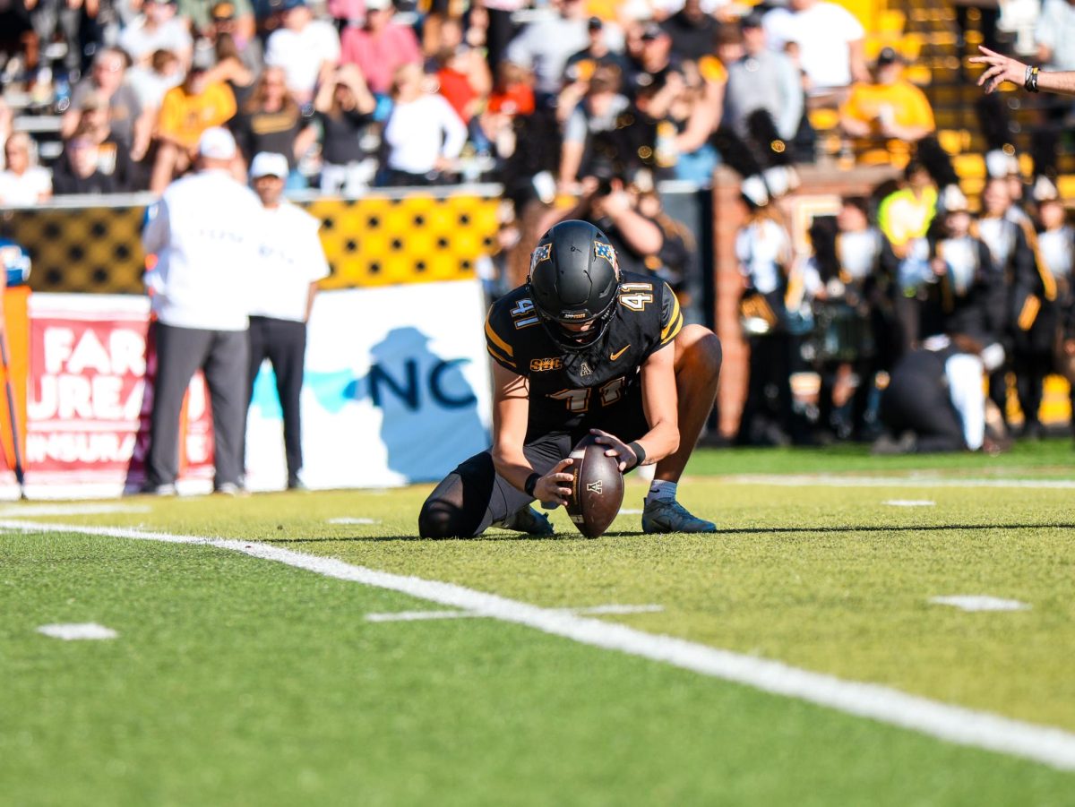 Punter Connor Maynard holds the ball for kicker Jackson Moore to score the extra point to end the half against Old Dominion on Nov. 2. Maynard is the Mountaineers’ starting punter.