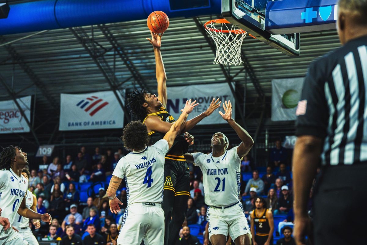 Guard Jamil Muttilib jumps up between two High Point players in an attempt to make a basket on Dec. 14. 
