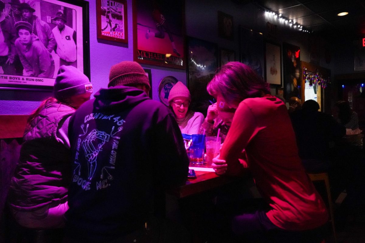 A trivia team confers over a table at Lily’s Snack Bar during trivia night on Jan. 27. The team, “Built To Swell,” said they have attended most trivia nights for almost a decade.