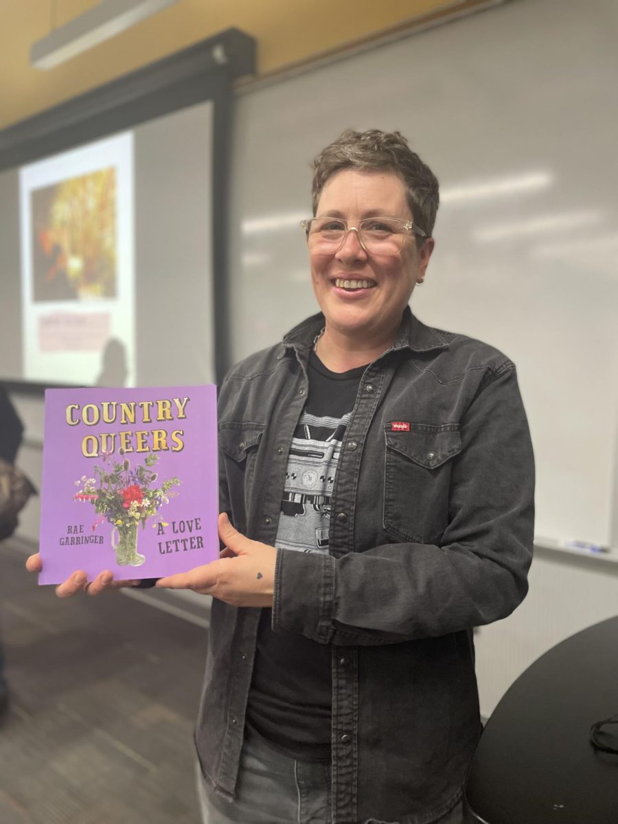 Rae Garringer poses with their book “Country Queers: A Love Letter” during the Country Queers panel event on Feb. 25.