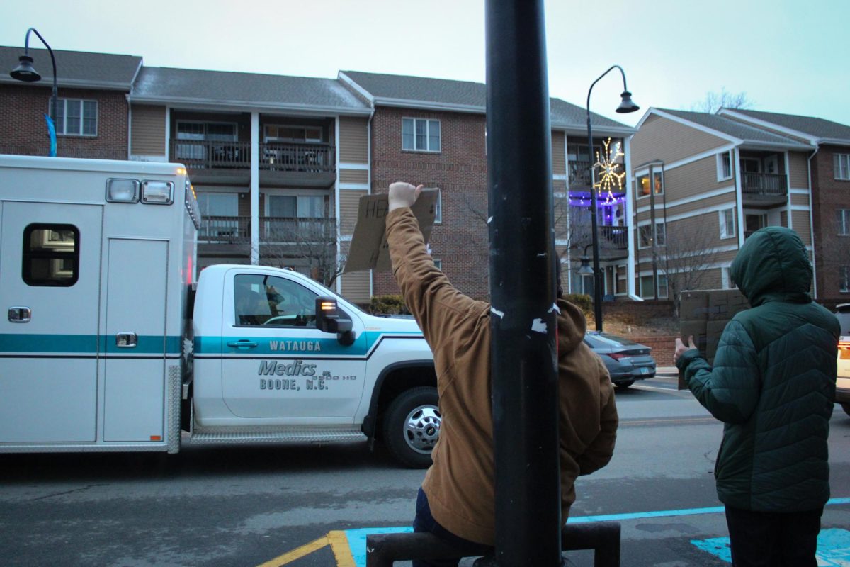 Demonstrators hold up signs that read “Honk 4 Healthcare” as Watauga Medics drive by on King Street on Feb. 16. 