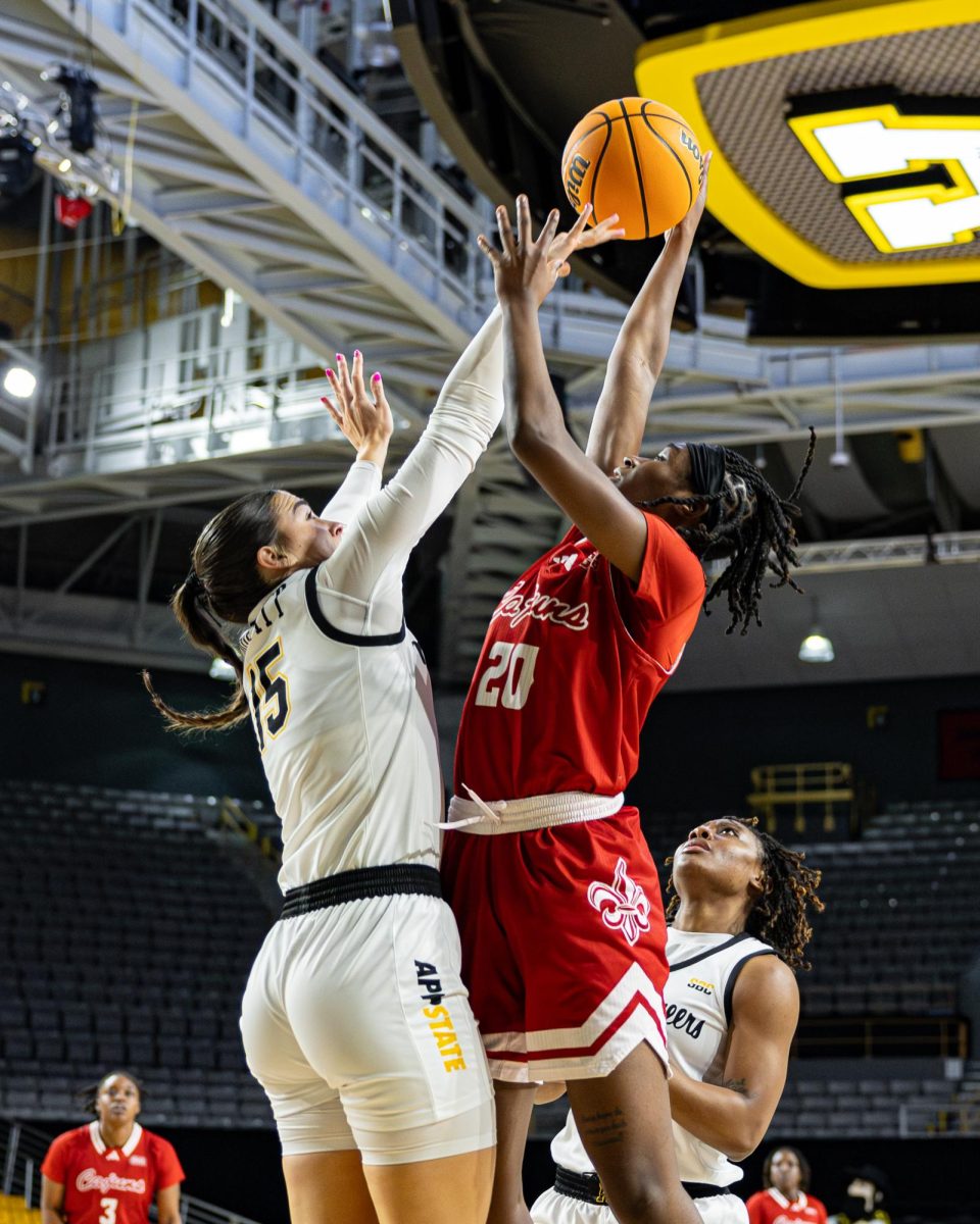 Junior forward Rylan Moffitt leaps and blocks a shot against the Louisiana Ragin’ Cajuns on Jan. 30.